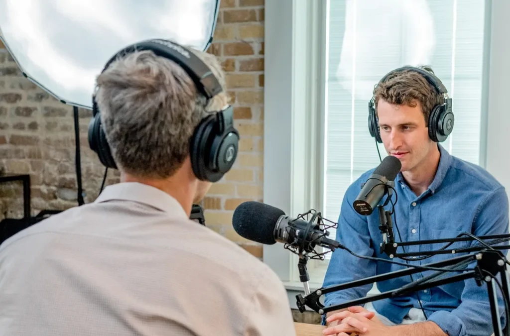 An older journalist interviews a younger, nervous interviewee in a studio but the interviewee is taking the time to think about his answers to make sure he gets the most from the experience.